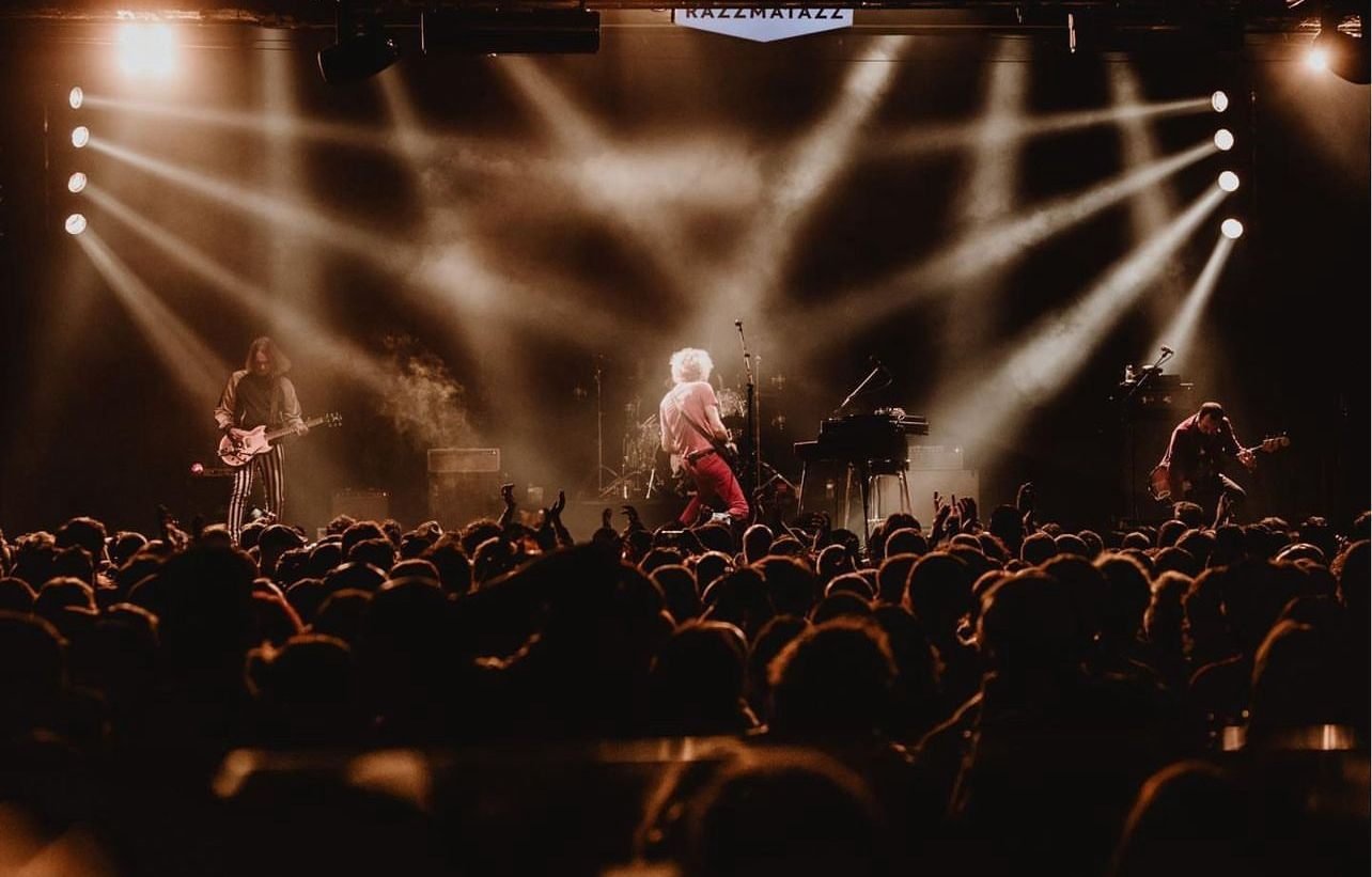 Banda en directo en Razzmatazz con luces cálidas y público